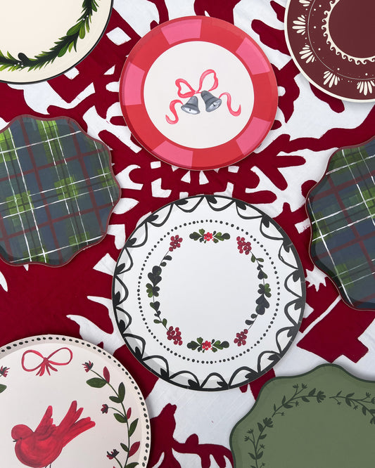 Collection of Christmas-themed plates with decorative patterns on a red and white background.