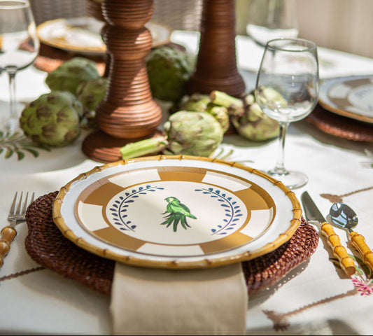 Decorative table setting with plates, glasses, and cutlery on a floral tablecloth.