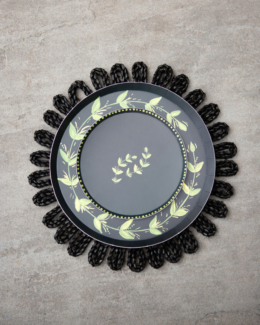 Decorative plate with a green leaf pattern set on a black charger