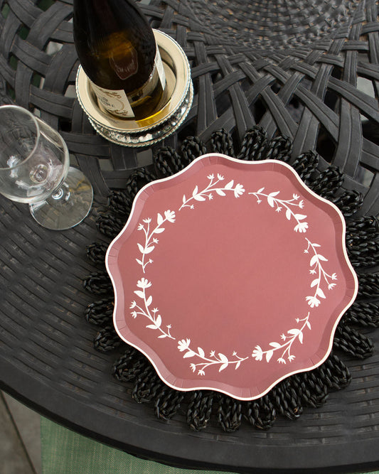 Pink decorative plate with white floral design on a black woven table