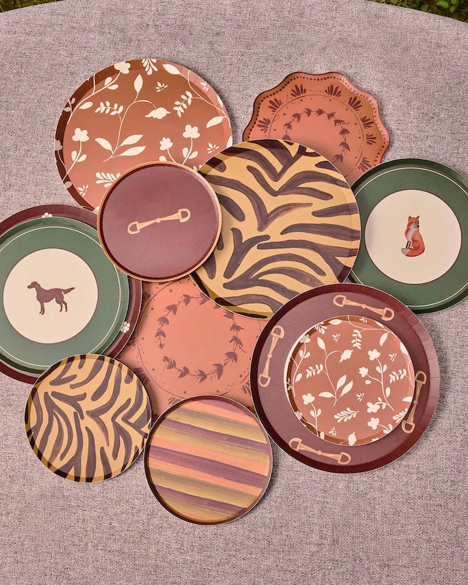 A collection of nine decorative plates with various patterns and colors, arranged in a circle on a textured gray surface.