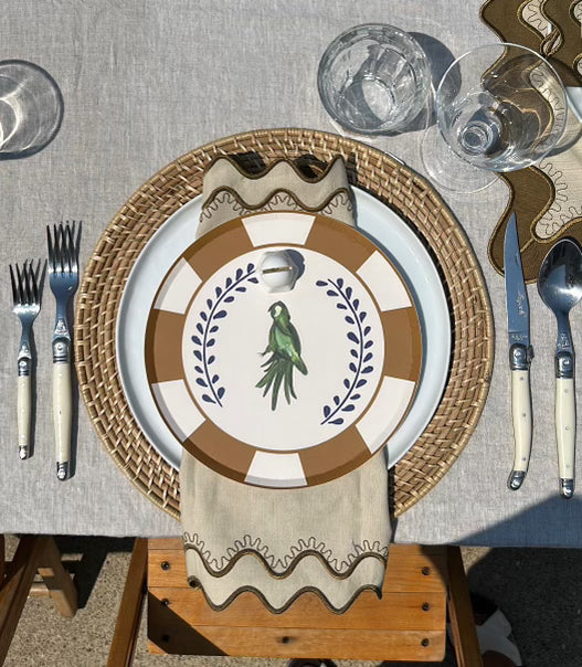 Dining table setting with decorative plates, cutlery, and glasses on a textured surface.