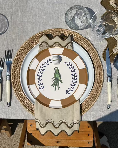 Dining table setting with decorative plates, cutlery, and glasses on a textured surface.
