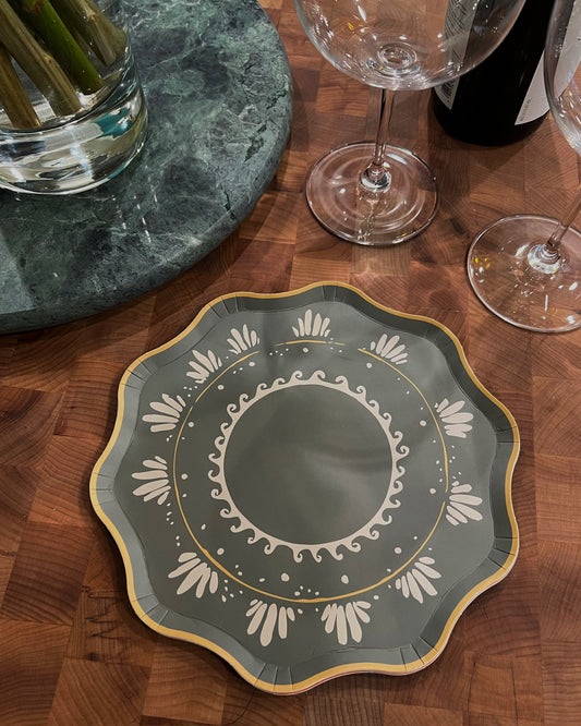 Decorative plate with intricate design on a wooden table with wine glasses and a marble coaster.