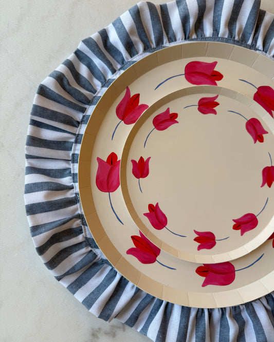 Set of paper plates with floral design and striped placemat on a neutral background