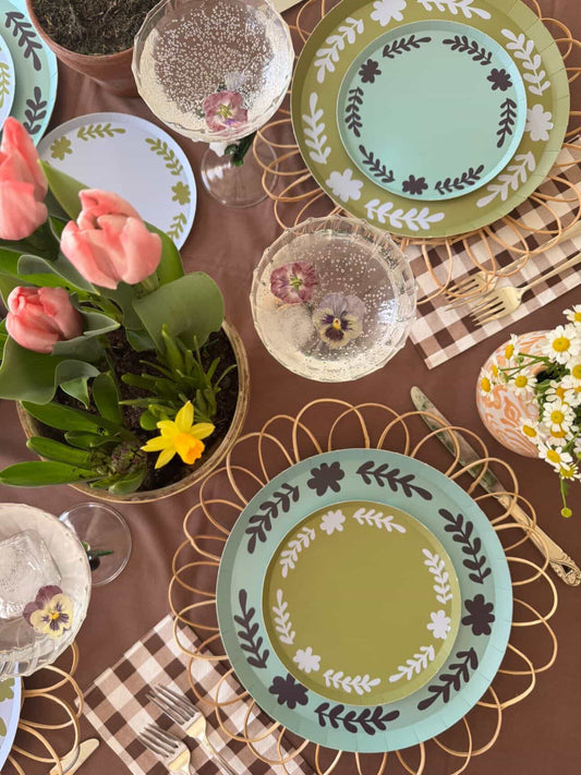 Decorative plates with floral patterns on a table setting with flowers and cutlery.