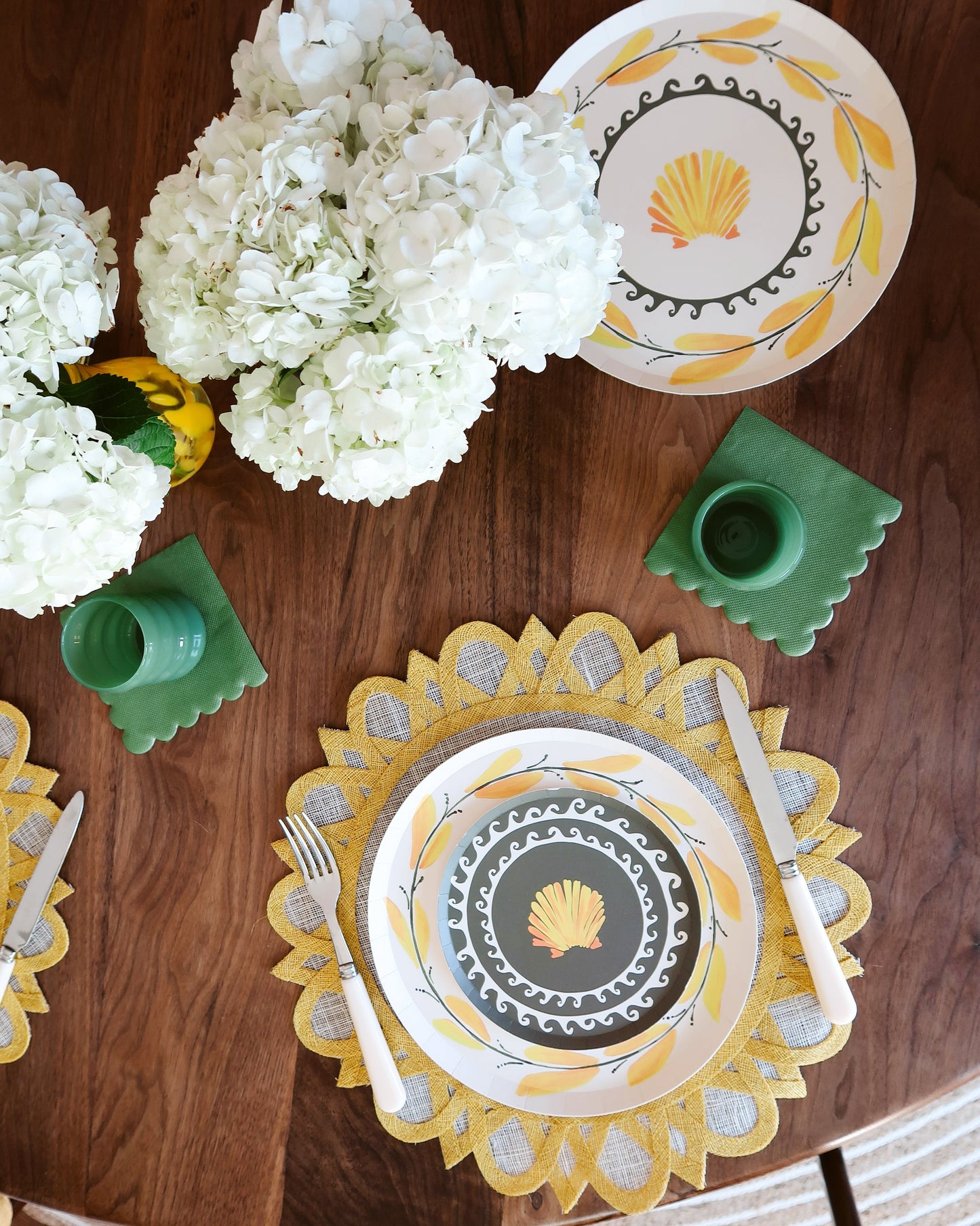 Decorative table setting with plates, cutlery, and flowers on a wooden table.