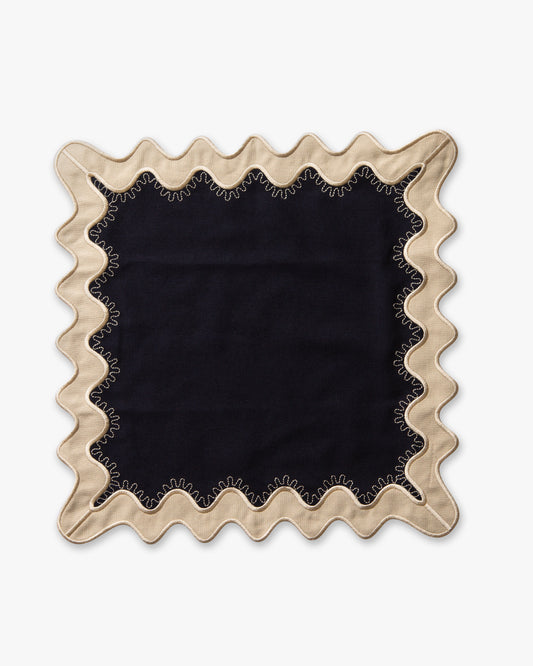 A navy linen napkin with white scalloped edges