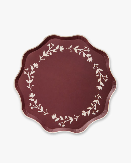 Maroon paper plate with white floral pattern on a white background