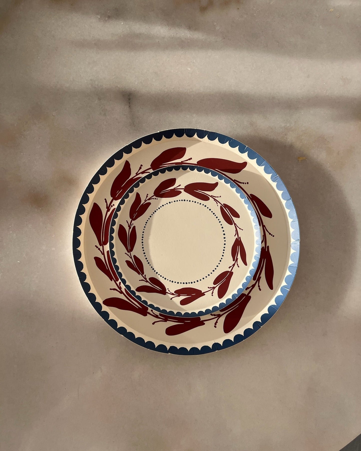 a red white and blue decorative plate with a leaf-like pattern