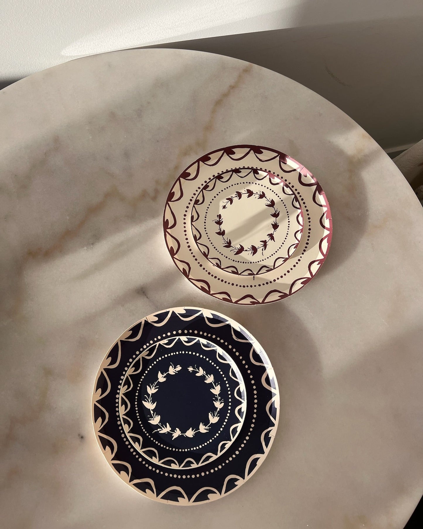 Two decorative plates with intricate designs on a marble surface