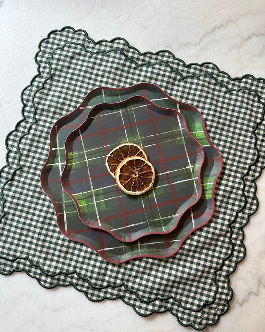 Stack of plaid plates on a checkered placemat with dried oranges.