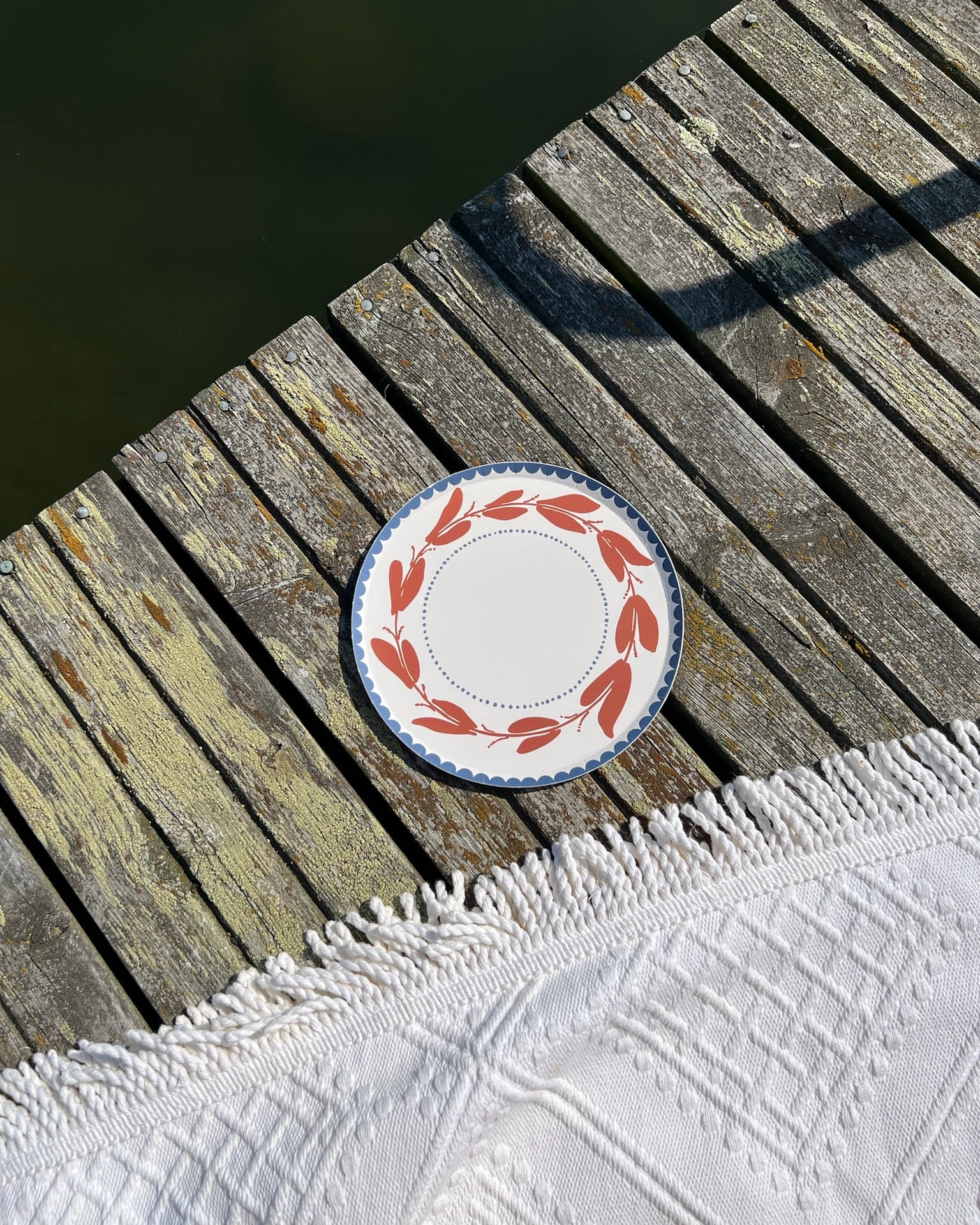 Decorative plate with red floral pattern on a wooden deck