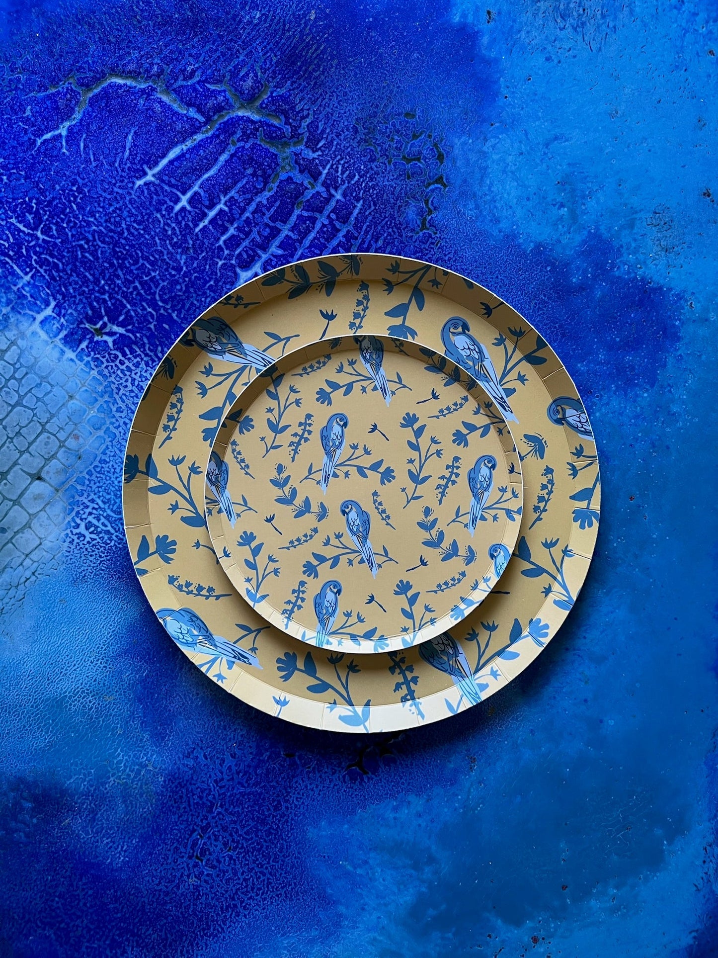 Set of three decorative plates with blue floral patterns on a textured blue background