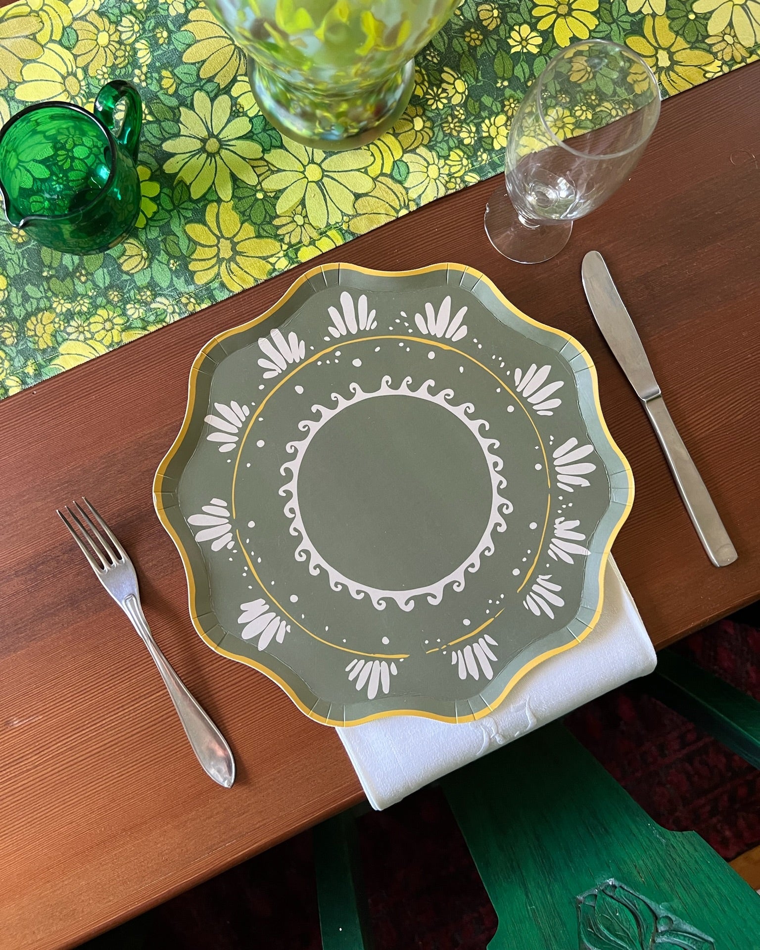 Decorative plate on a table with a fork, knife, and glasses.