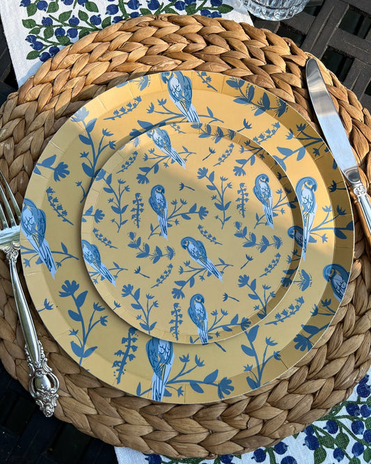 Set of yellow plates with blue bird pattern on a woven placemat
