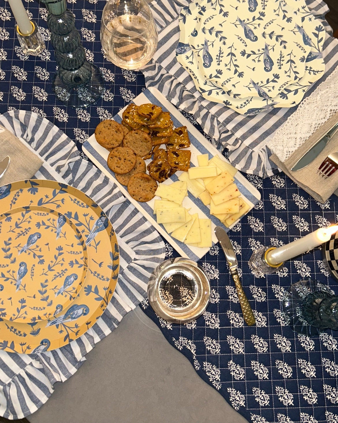 Table setting with plates, cutlery, and food on a patterned tablecloth.