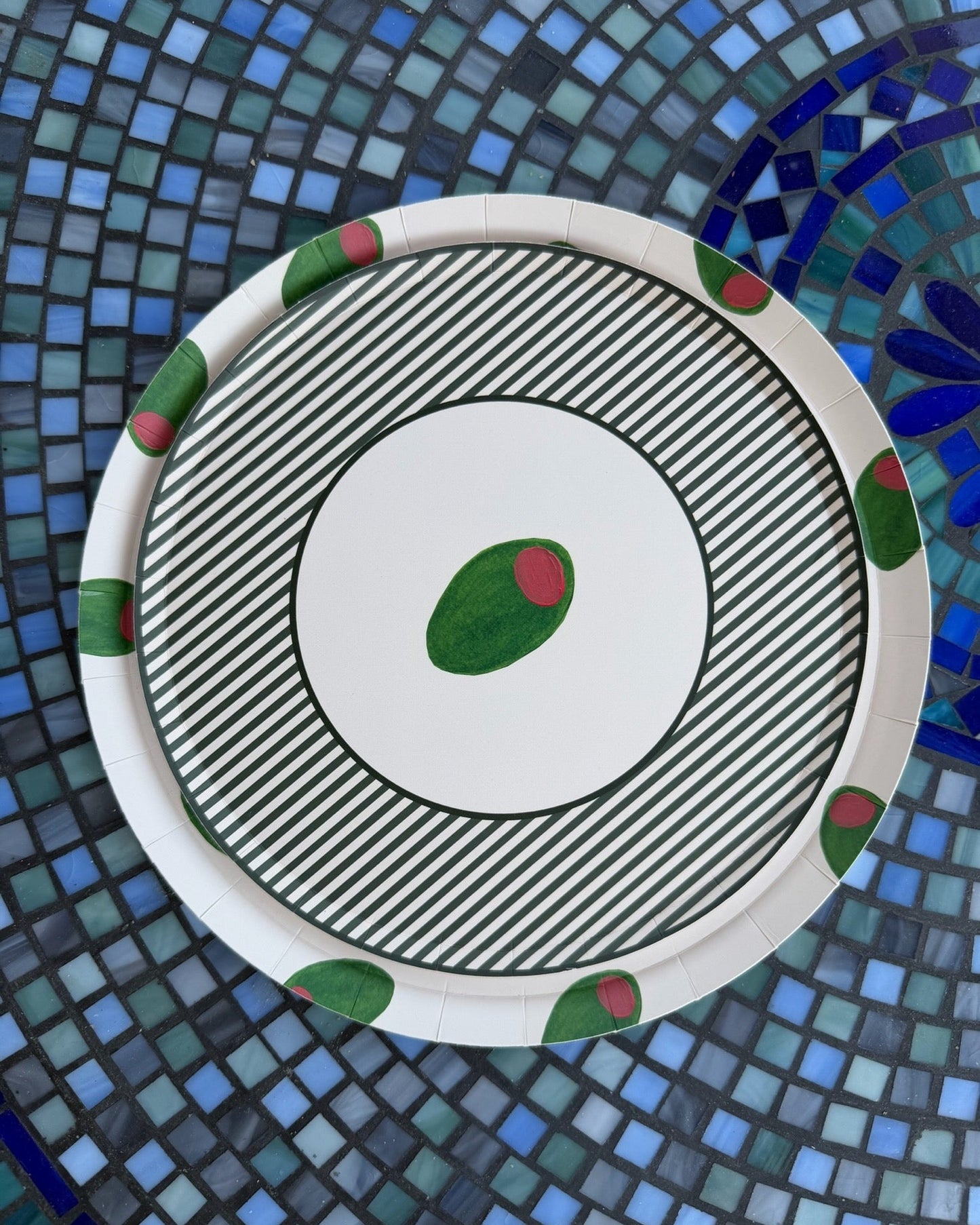 Two plates stacked that have green olives on them