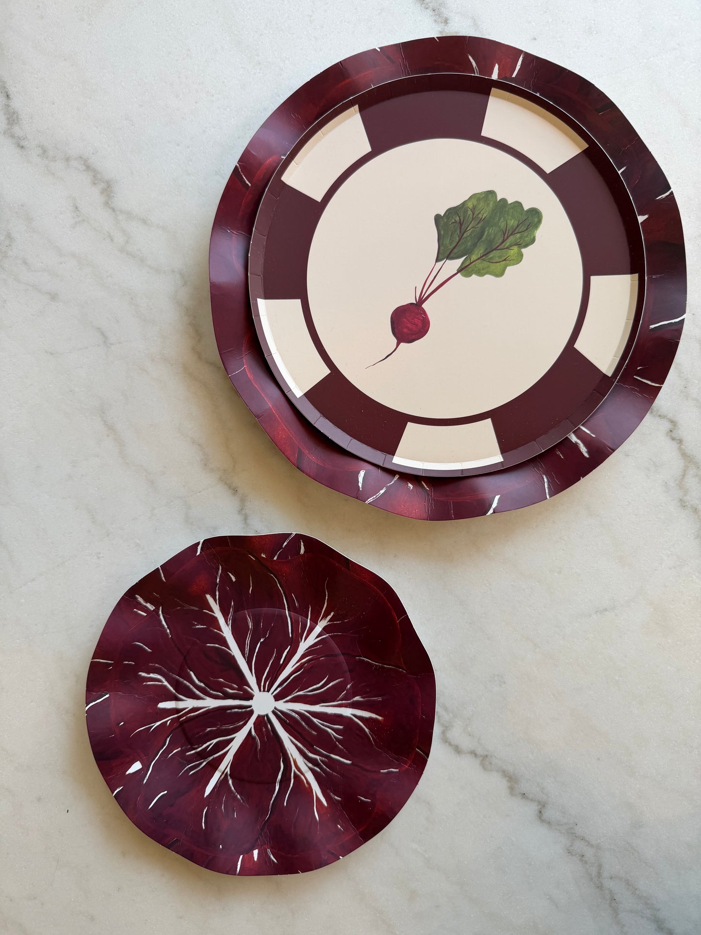 Two decorative plates with beetroot designs on a marble surface