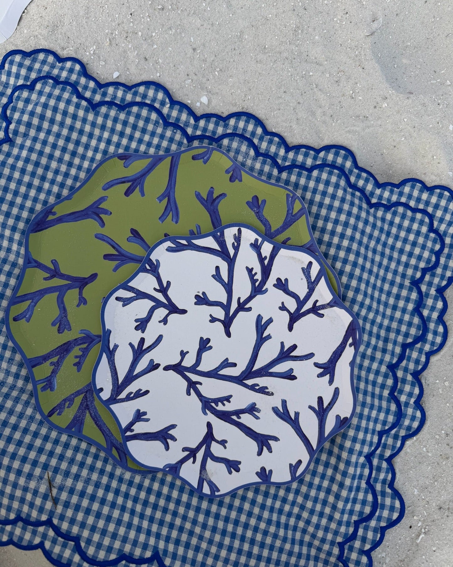 Decorative paper with blue and green coral patterns on a checkered placemat in the sand