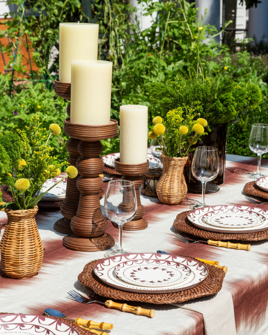 Decorative outdoor table setting with candles, plates, and glasses.
