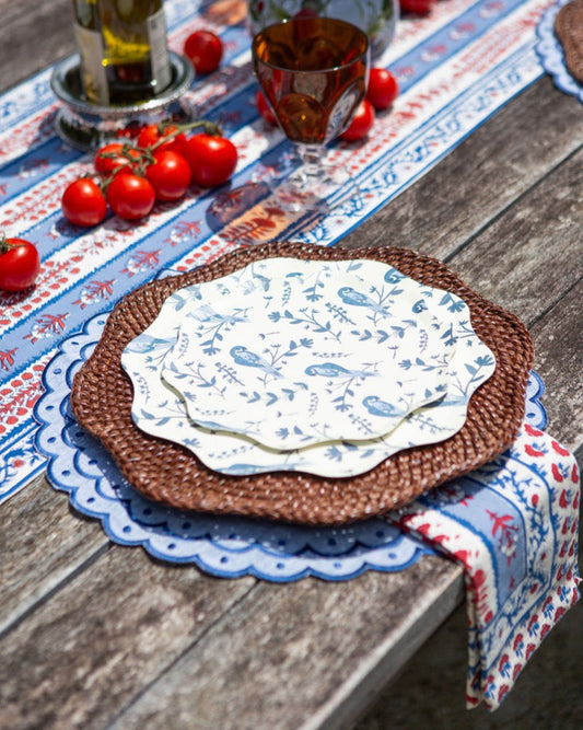 A table setting with blue toile plates on a rattan charger plate with blue placemats