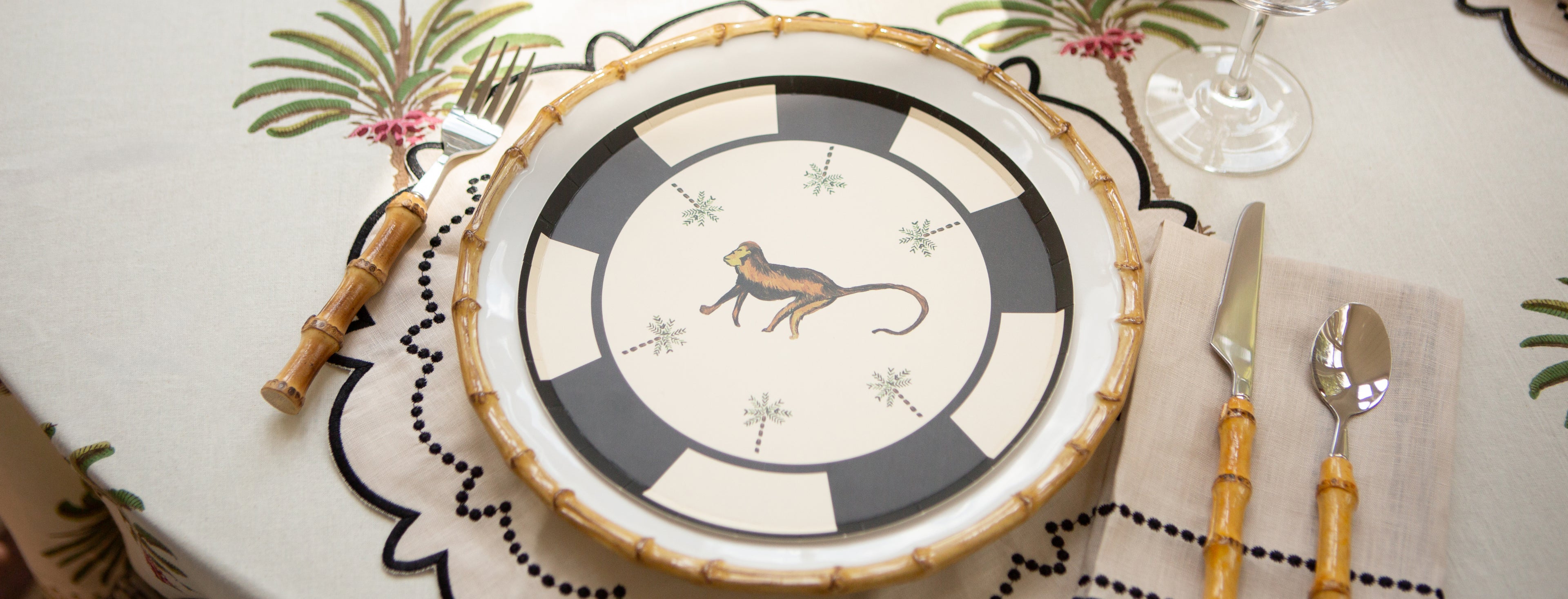 Decorative plate with a monkey design on a table setting with cutlery and placemats.