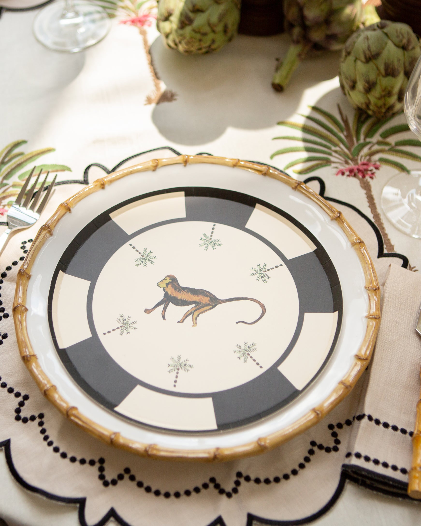 Decorative plate with a monkey design on a table setting with cutlery and placemats.