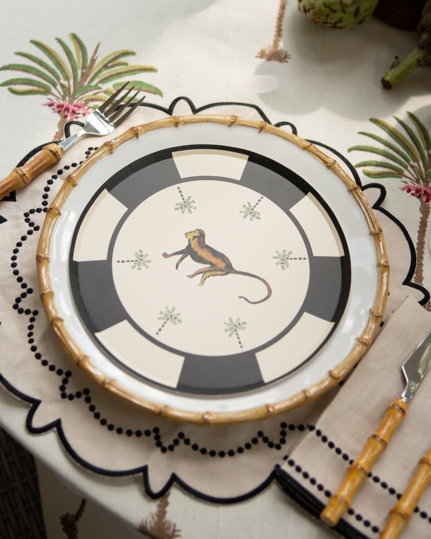 Decorative plate with a monkey design on a table setting with cutlery and placemats.