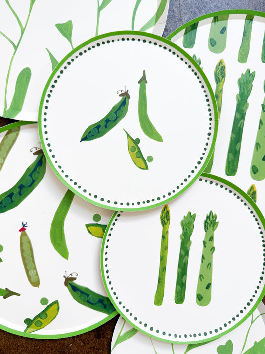 A stack of plates with sweet peas and asparagus on them
