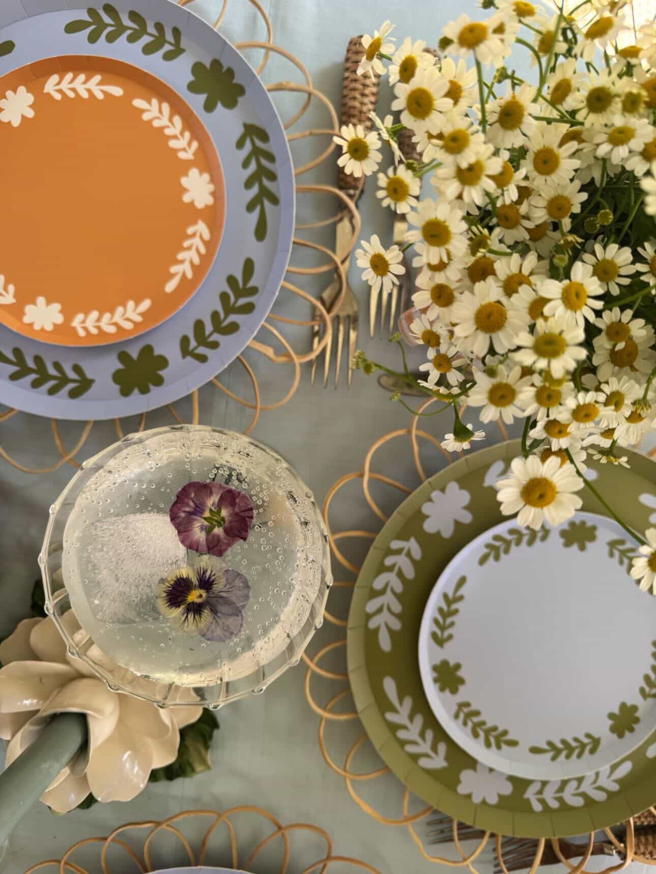 Decorative plates with floral patterns on a table setting with flowers and cutlery.
