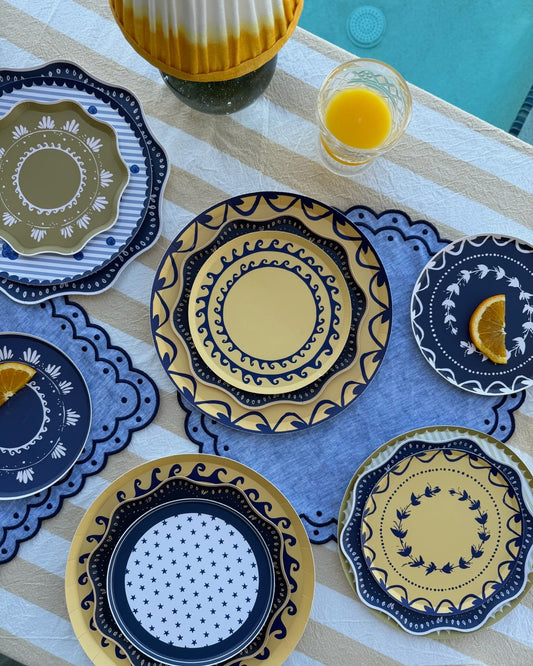 Stacked decorative plates on a striped table cloth next to a pool