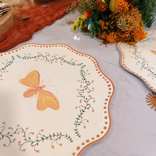 Decorative table setting with a butterfly design on the plate, flowers, and a bowl.