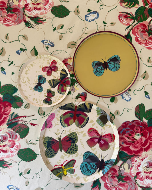 decorative plates with different butterfly patterns set on a floral table cloth.
