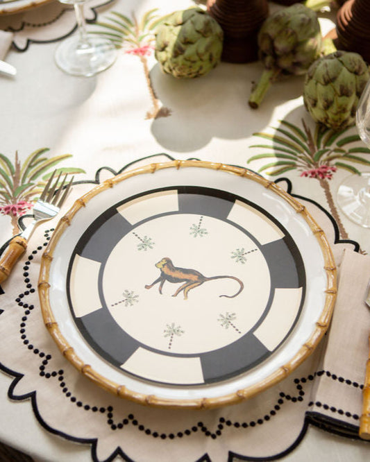Decorative plate with a monkey design on a table setting with palm tree placemats.