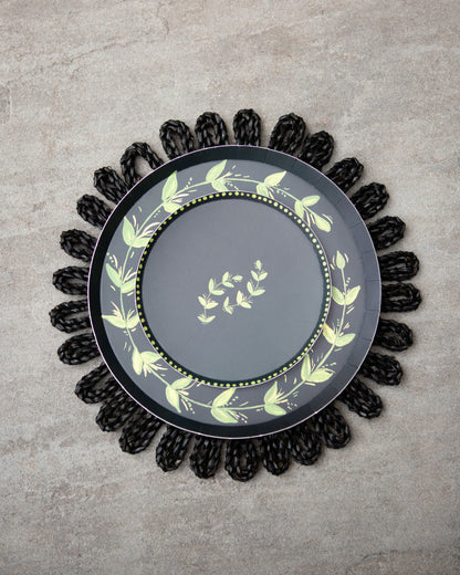Decorative plate with a green leaf pattern set on a black charger 