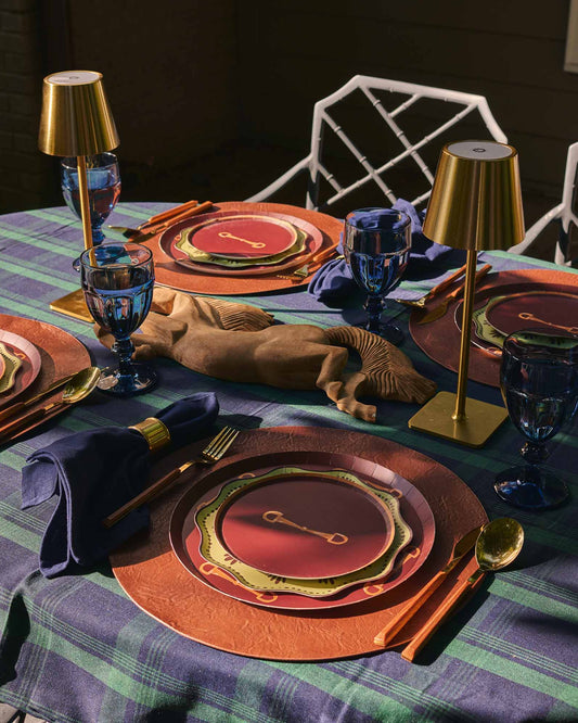 a table setting outdoors with horse themed plates and a blue and green plaidtablecloth 