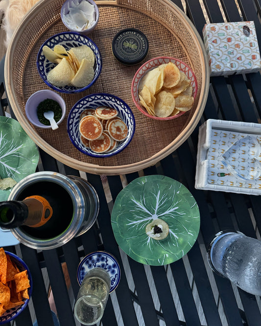 Table setting with snacks, drinks, and decorative items on a woven tray.