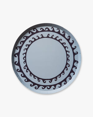 Round decorative blue plate with wavy line pattern on a light gray background