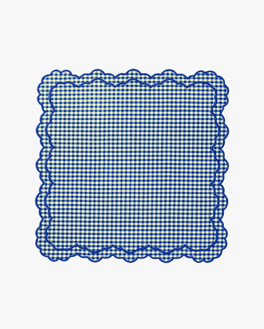 Blue and white checkered doily with scalloped edge on a white background