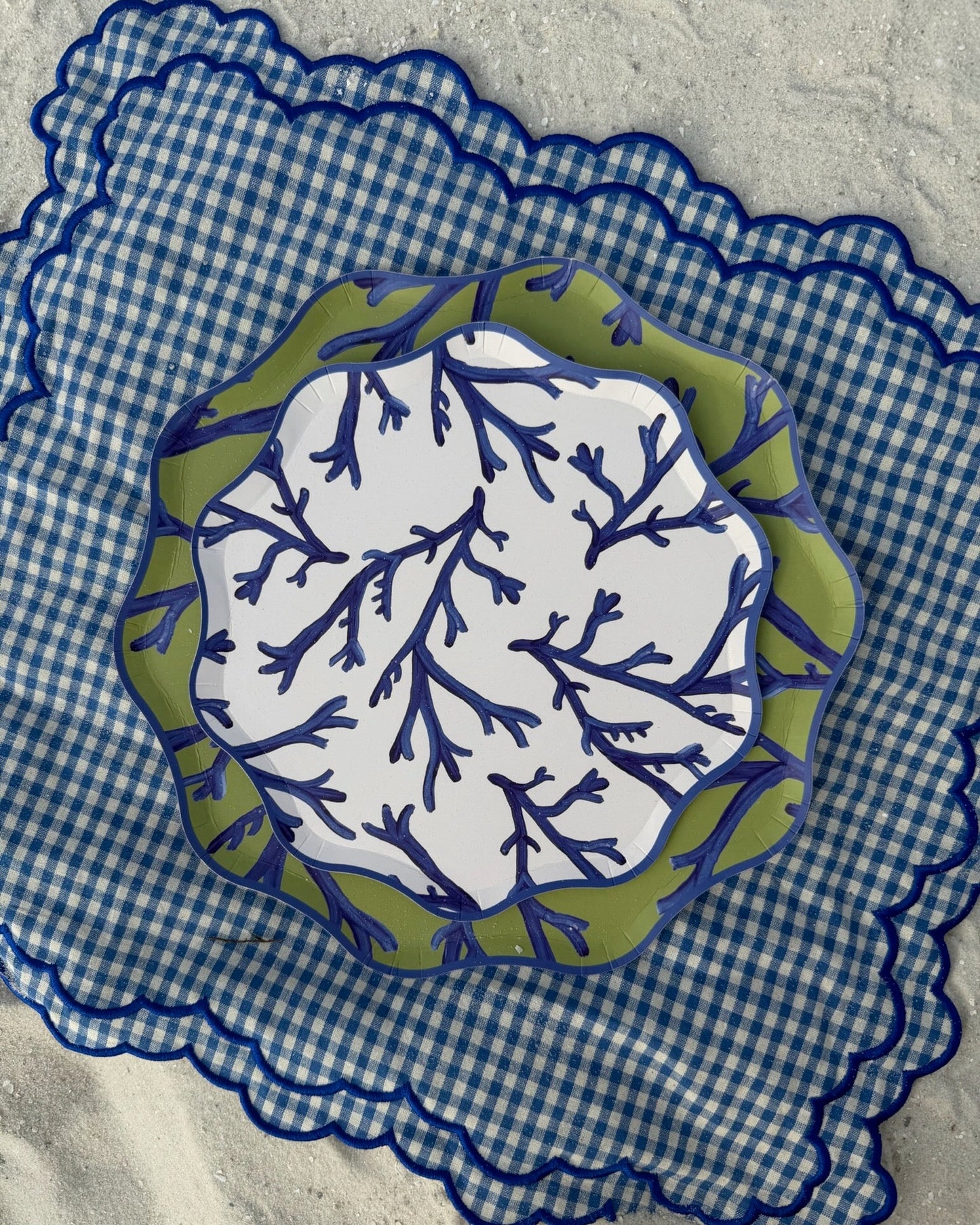 Decorative plate with blue and green leaf pattern on a blue checkered placemat