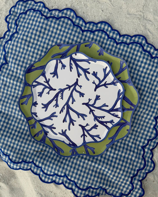 Decorative plate with blue and green leaf pattern on a blue checkered placemat