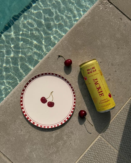 A plate with cherries on it sitting next to a pool 