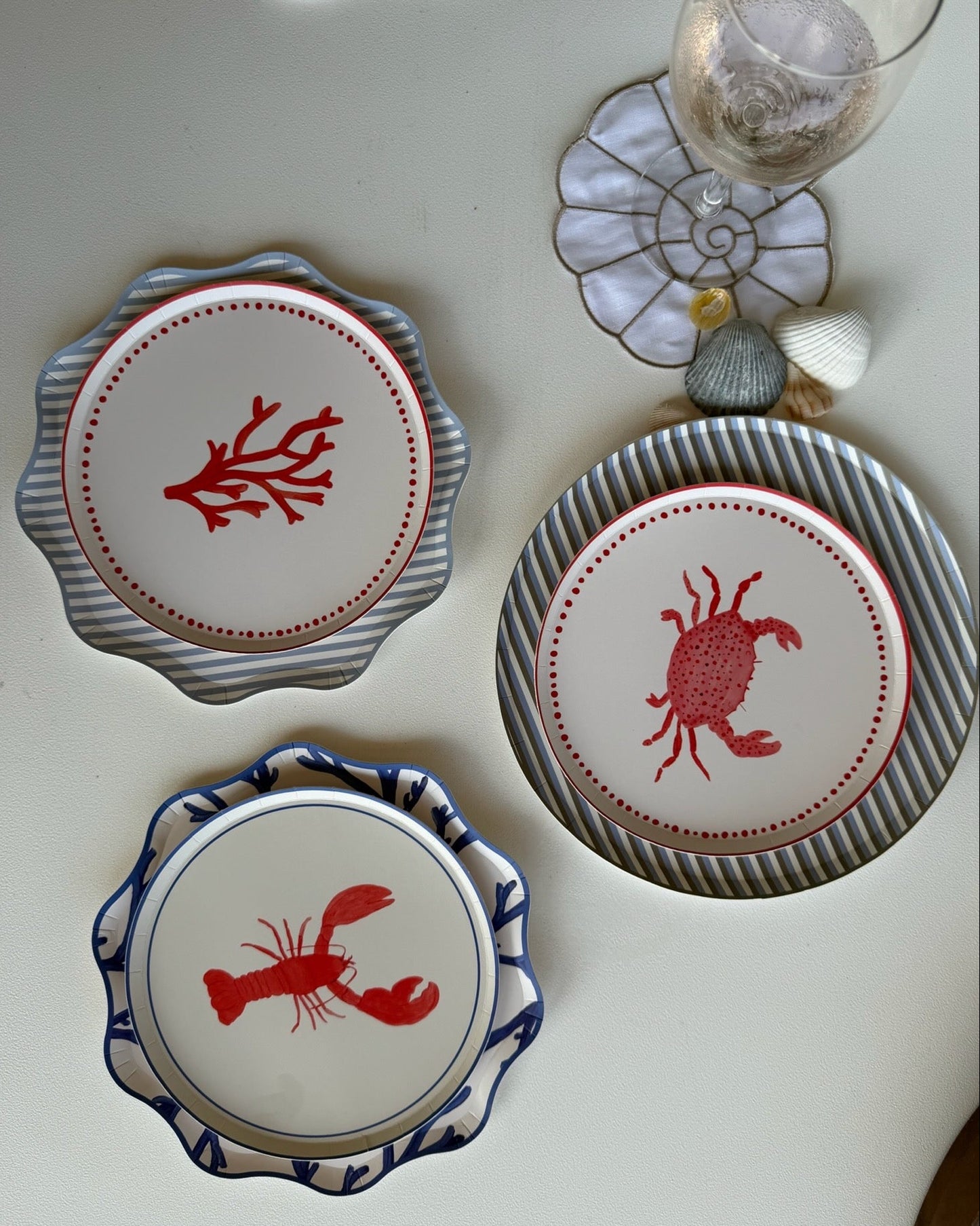 Maritime themed plates on a white table with a glass of wine