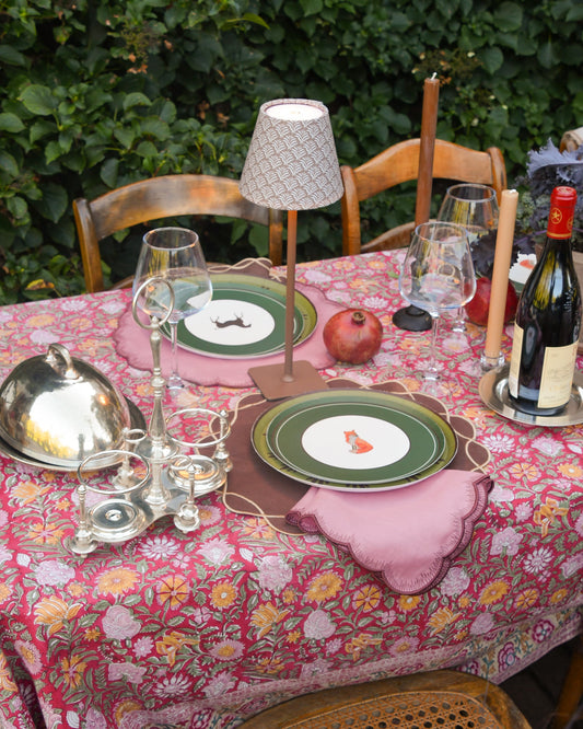 a decorated outdoor table with two plates layered on top of a linen placemat. The top plate has an image of an orange fox. 