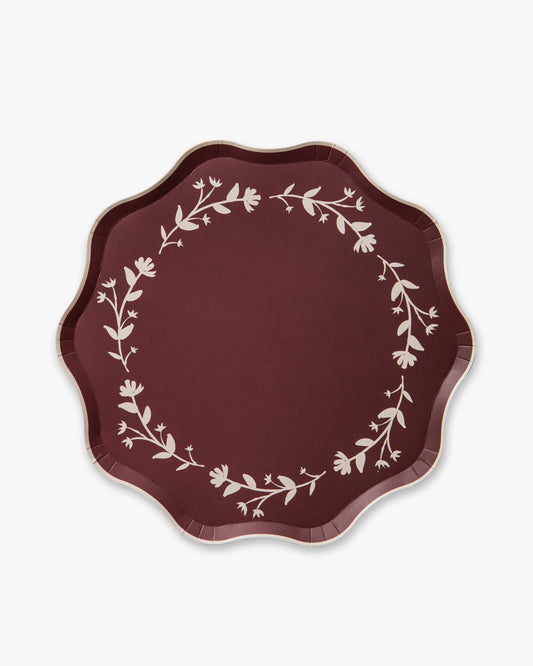 Round maroon plate with white floral patterns on a white background