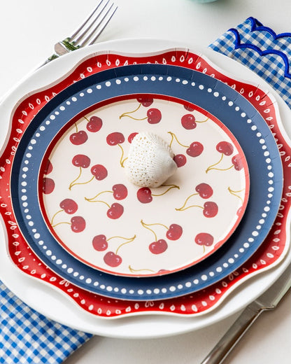 Stack of decorative plates with cherry pattern on a white tablecloth.