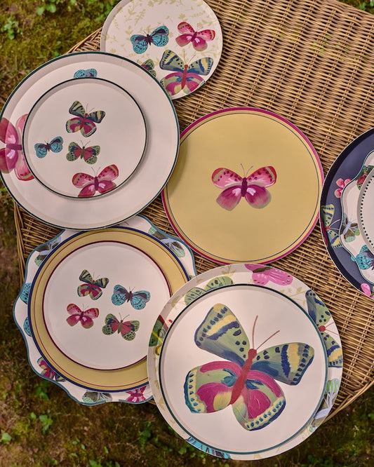decorative plates scattered on a whicker table. The plates have butterflies on them.