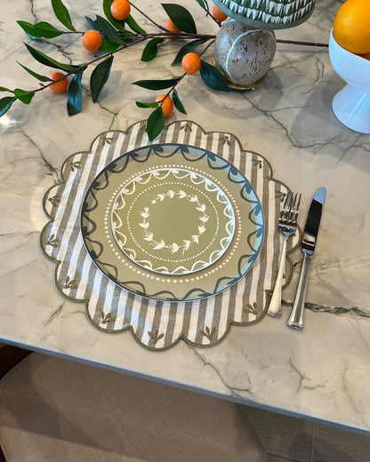 Decorative green plates on a striped placemat on a marble surface. 