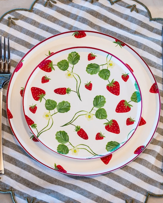 decorative plates with strawberries on them at a table setting